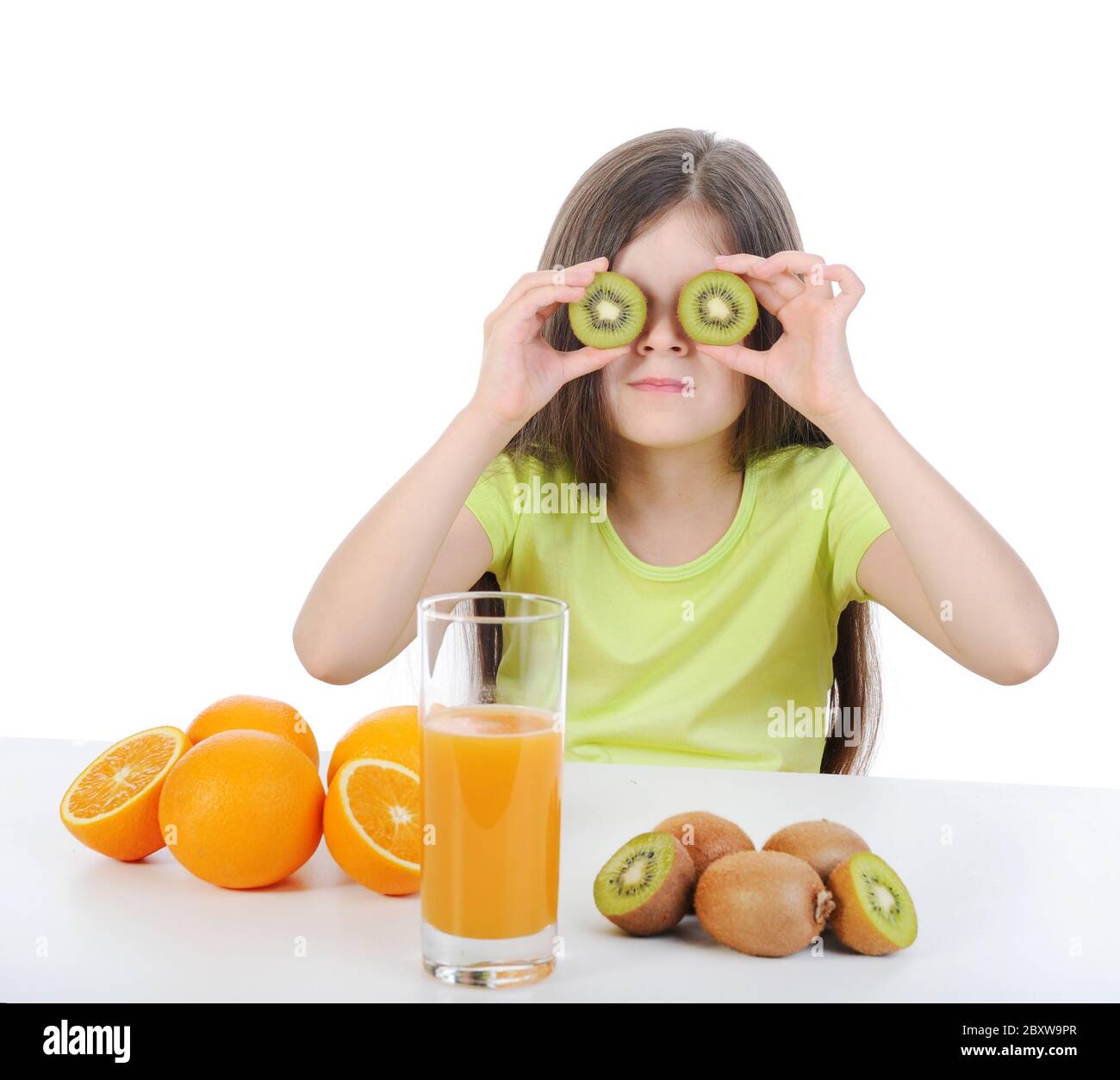 Girl with a kiwi at the table. Stock Photo