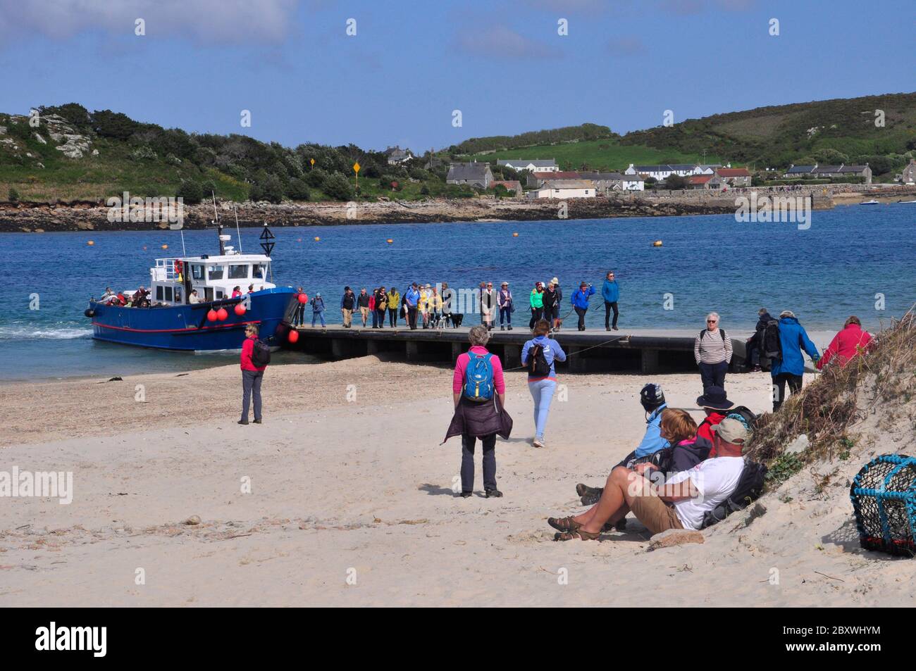 The inter island boat 'Voyager' belonging to the island of St Martin's, disembarking  passengers at Annake's Quay on Bryer,while tourists wait on the Stock Photo