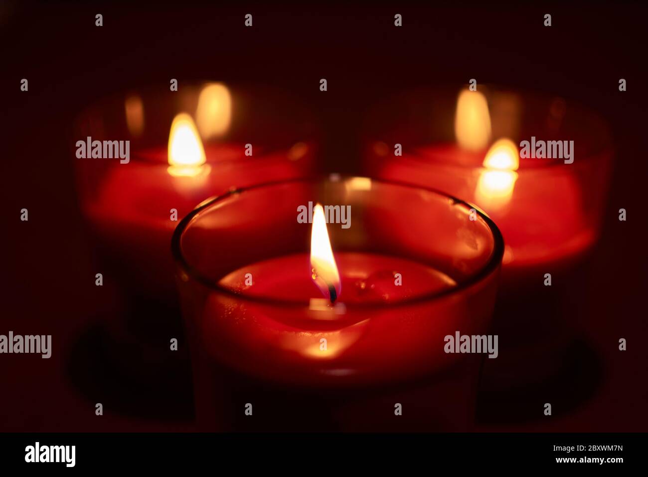 Three pretty burning red candles Stock Photo Alamy