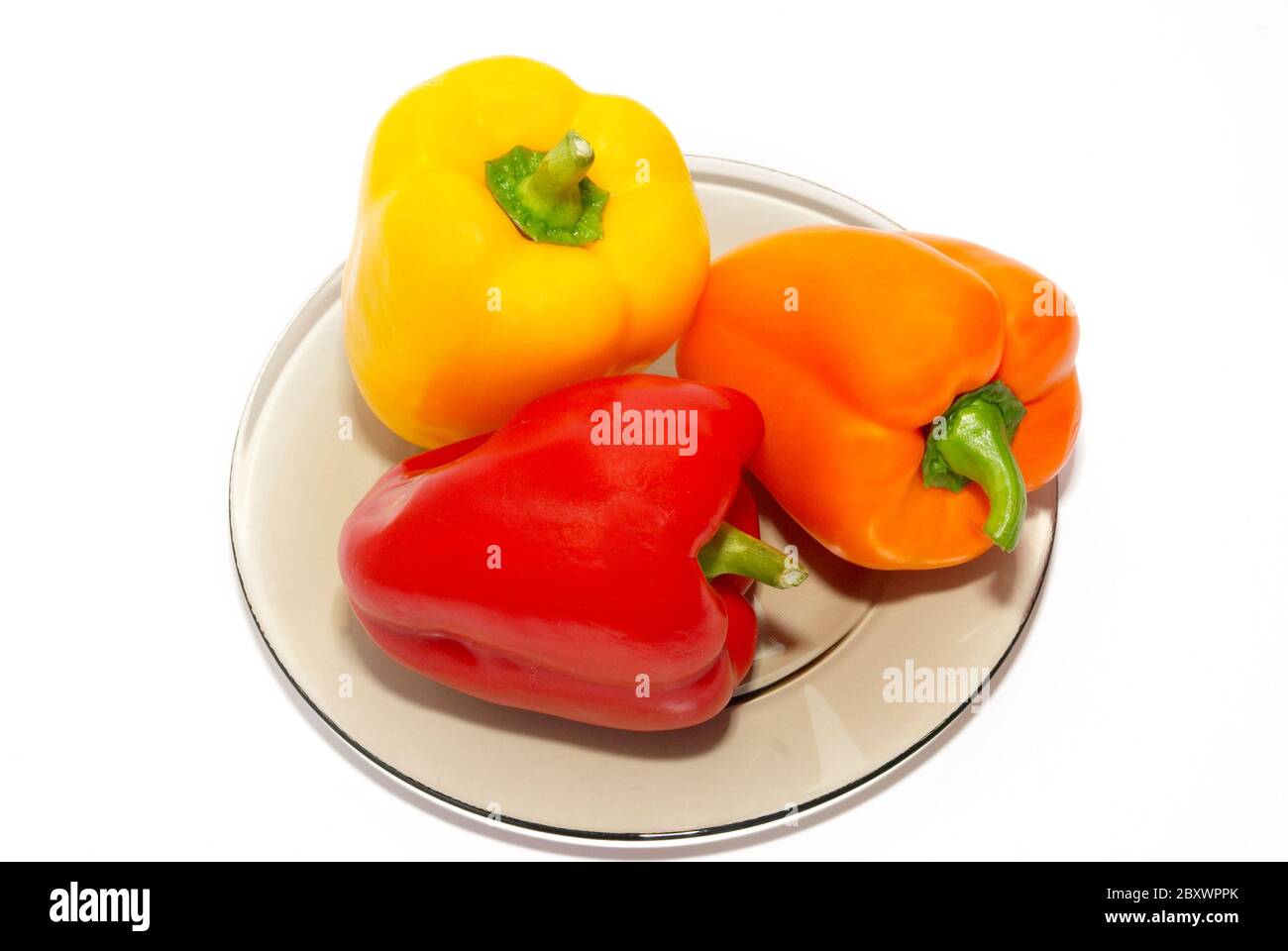 Three colored paprika on the plate on white background Stock Photo - Alamy