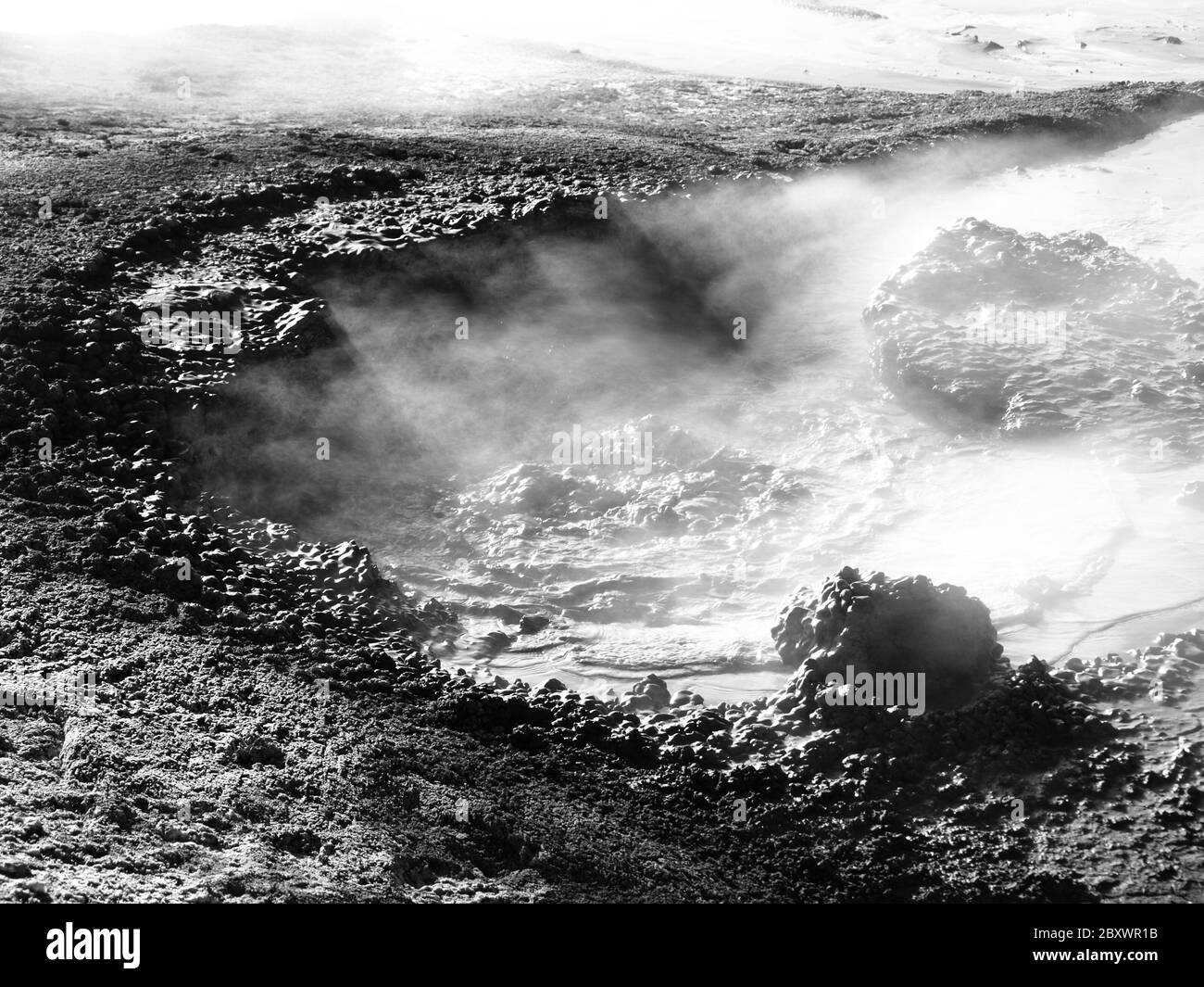 Steam escaping from mudpot and illuminated by sun rays, Sol de Manana, Altiplano, Bolivia, black and white image Stock Photo