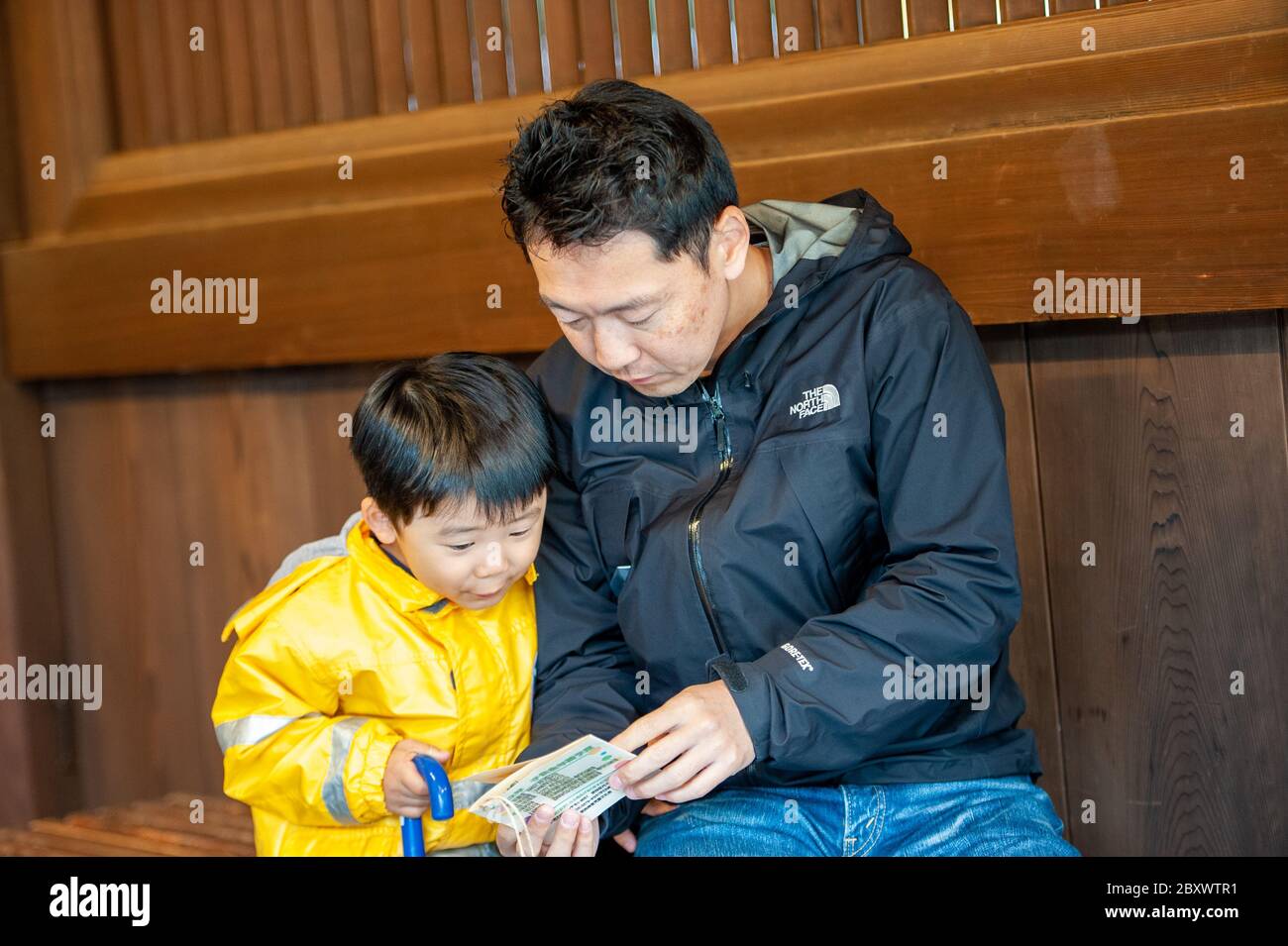 A Japanese boy and his father waiting for the harvest festival and rehearse a song from a book, at Meiji Shrine in Tokyo, Japan Stock Photo