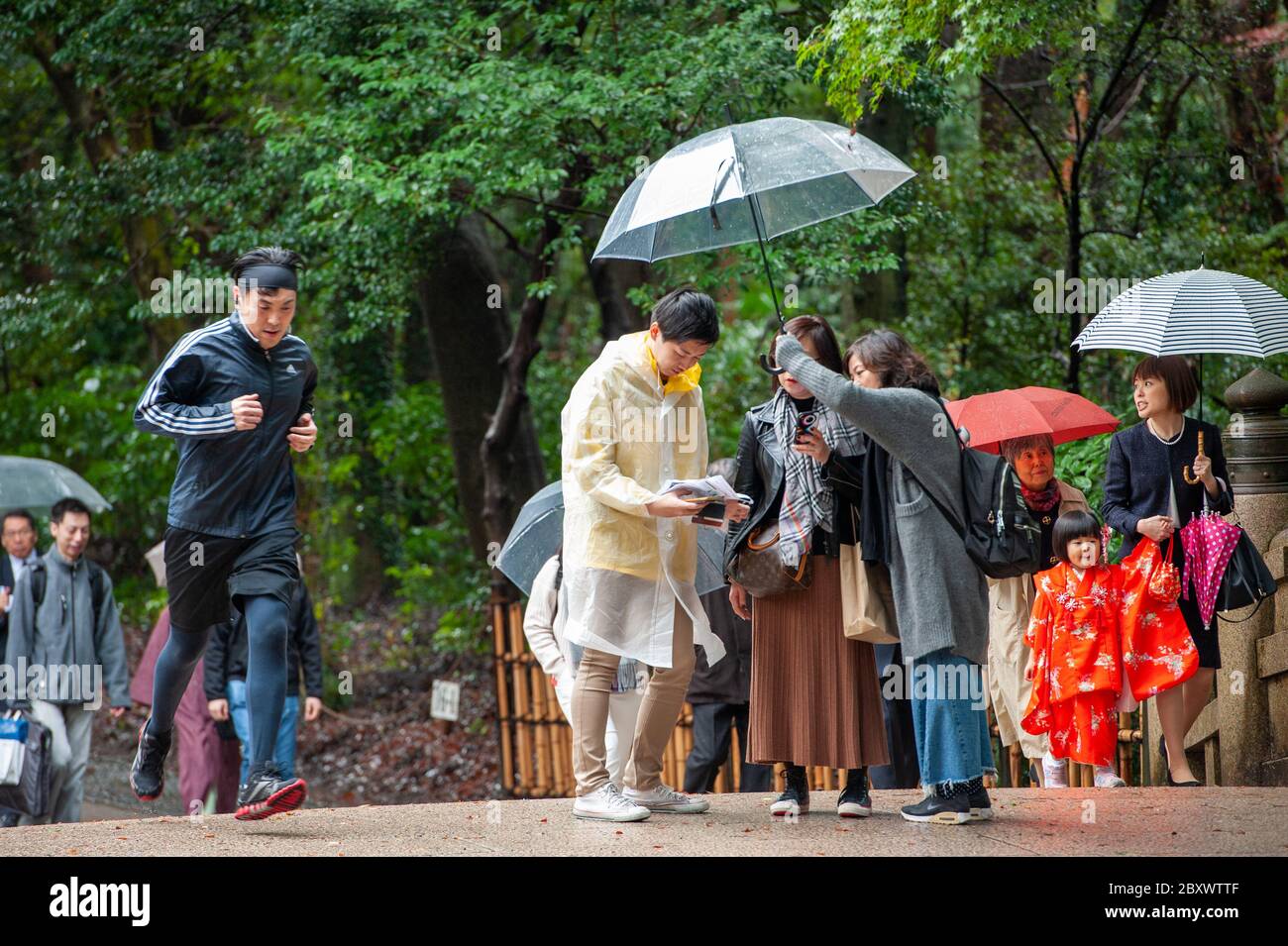 Families with children and visitors including the occasional jogger on the main path entering Meiji Shrine in Tokyo, Japan Stock Photo