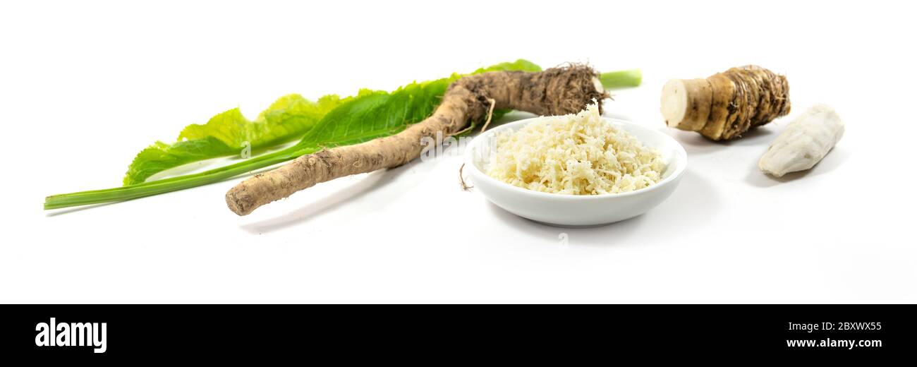 Grated horseradish in a bowl, fresh roots and leaves in panoramic
