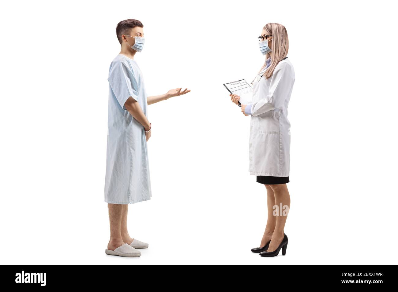 Full length profile shot of a young male patient talking to a female doctor and wearing protective masks isolated on white background Stock Photo