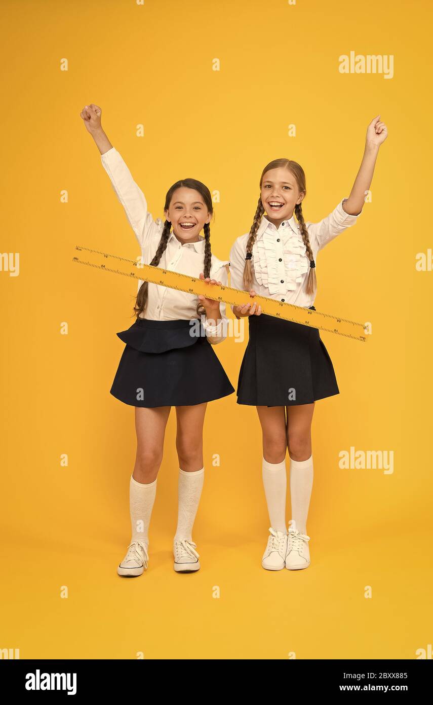 Measuring equipment. Kids students study math. Knowledge day. Schoolgirls school uniform hold big ruler. Geometry school lesson. Teamwork concept. Close or far. Measuring skills. Measuring distance. Stock Photo