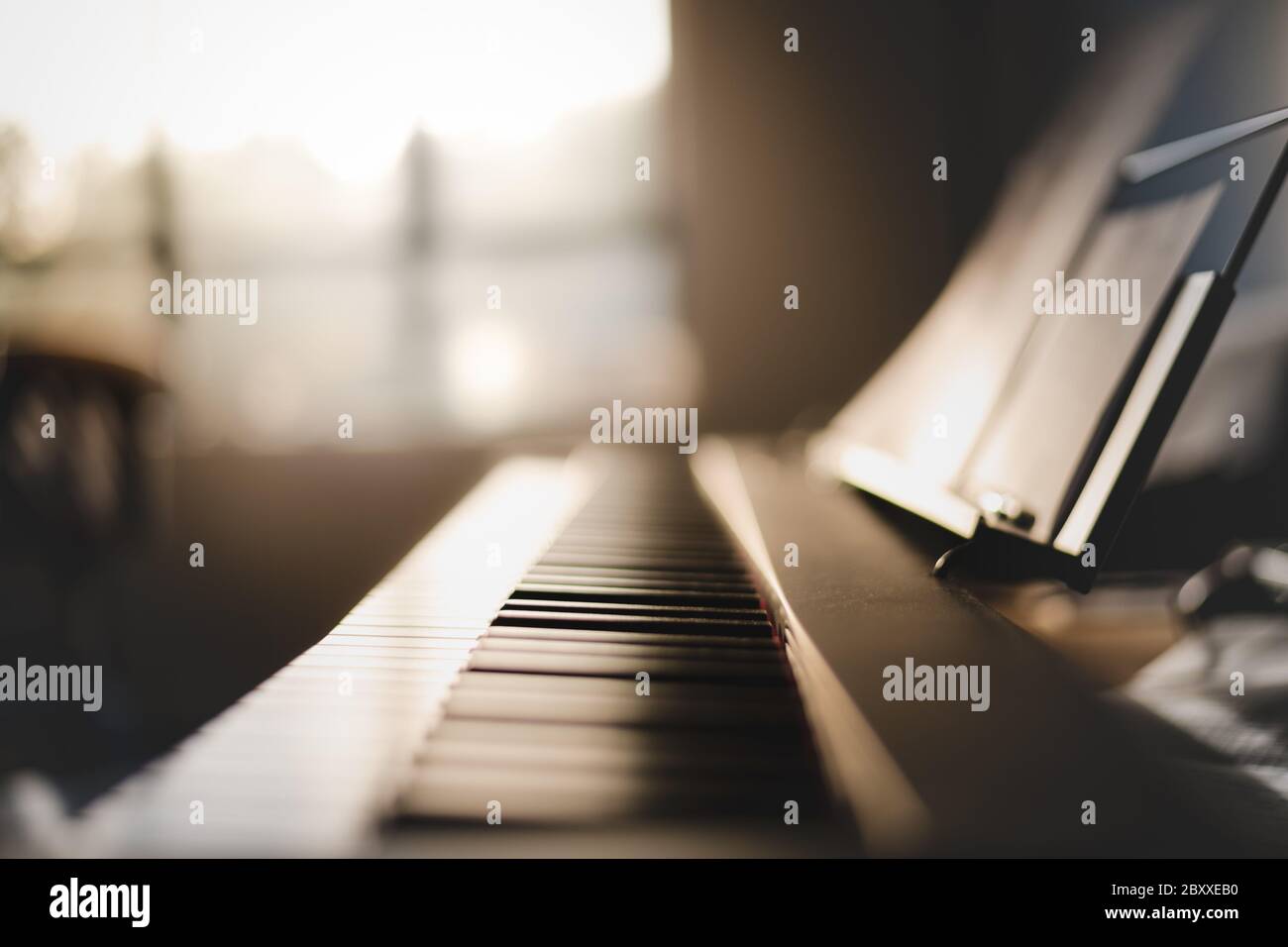 Length shot of 88 key piano keyboard inside a home with morning golden