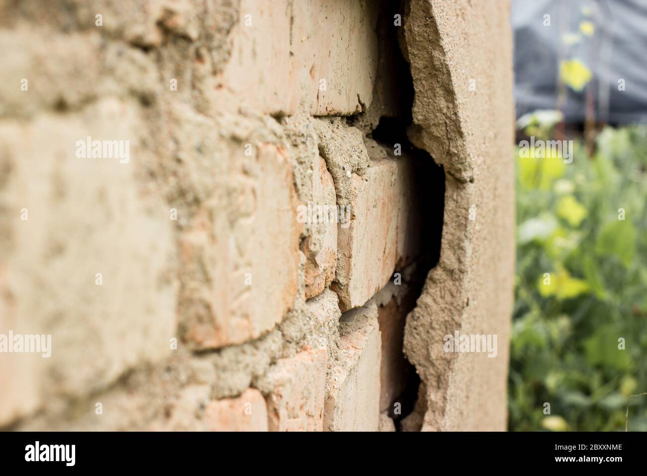 Non technology plaster. Building cracked plaster facade wall with brick. Stock Photo