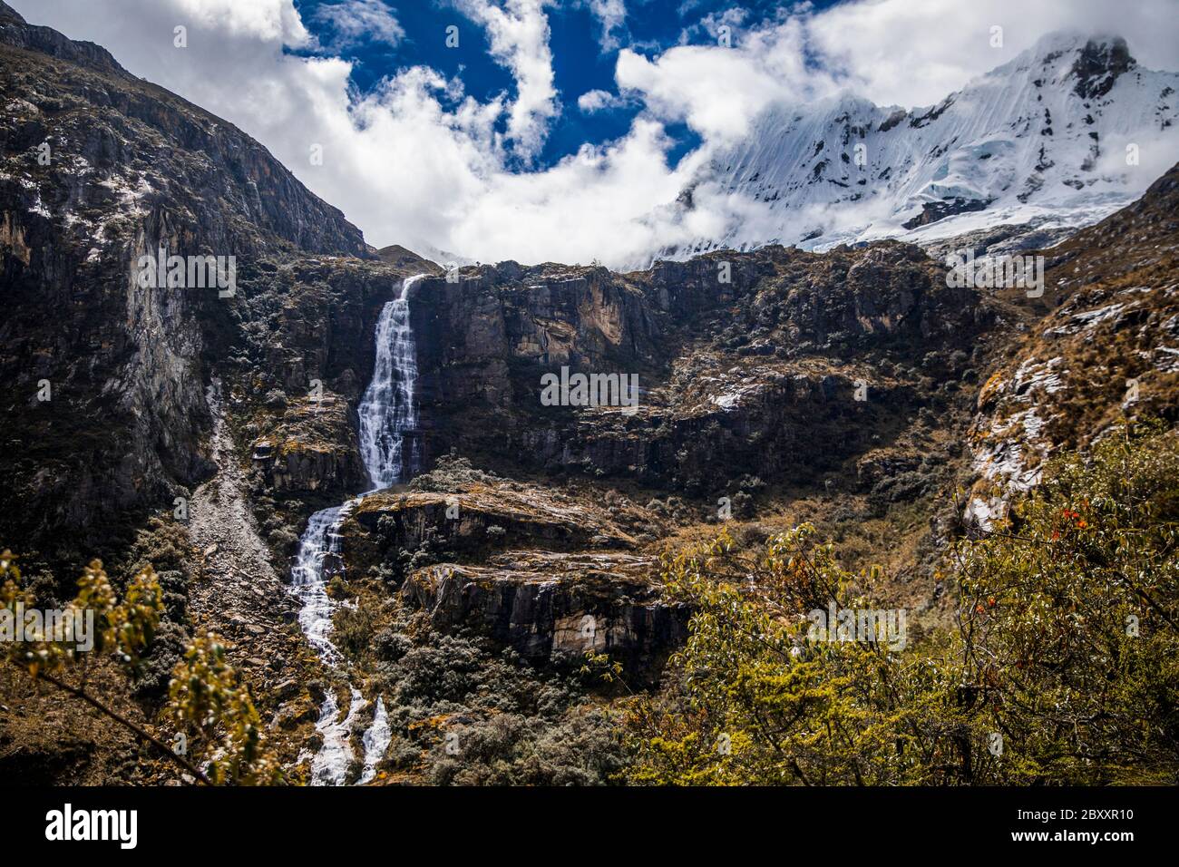 waterfall in mountains, trees, clouds and blue sky Stock Photo