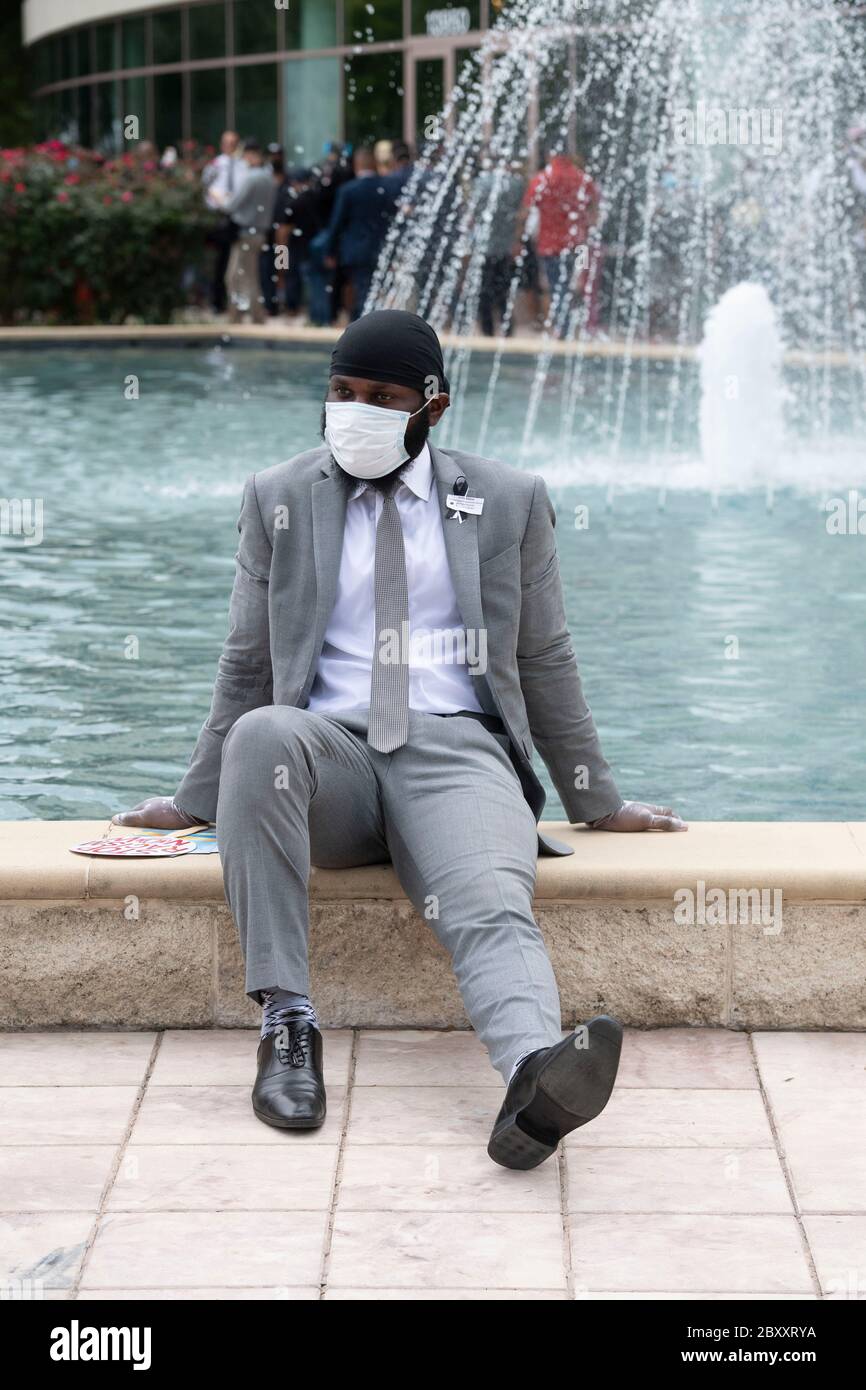 A young man wearing a face mask takes a break before entering Fountain of Praise church during a public visitation for George Floyd. Floyd's death two weeks ago at the hands of a white police officer in Minneapolis has spawned hundreds of anti-racism and anti-police brutality protests worldwide. Stock Photo
