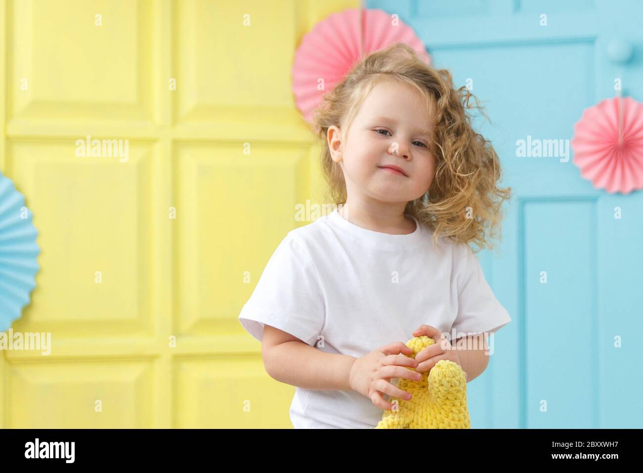 A happy child on a colored background. Holding a toy. Stock Photo