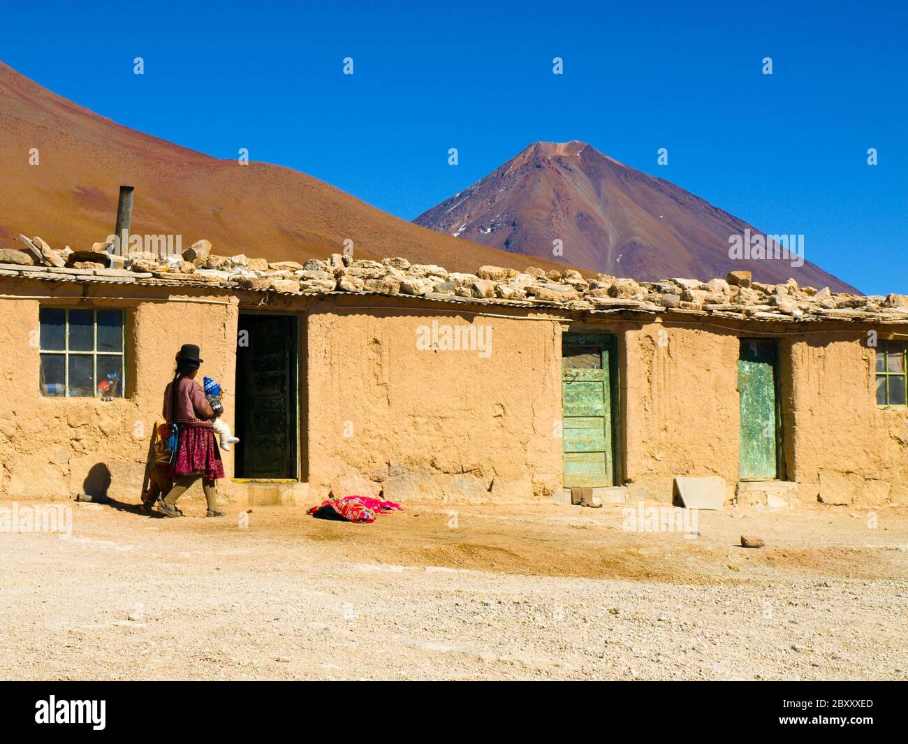 Basic house made of adobes and bolivian woman in typical dress. Licancabur  volcano on background, Altiplano, Bolivia Stock Photo - Alamy