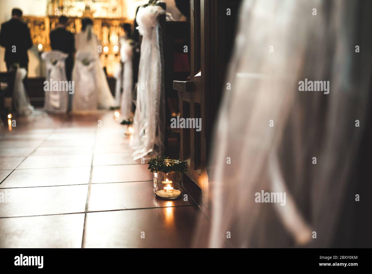 Low profile view of aisle in church lined with candles during wedding ceremony. Wedding day