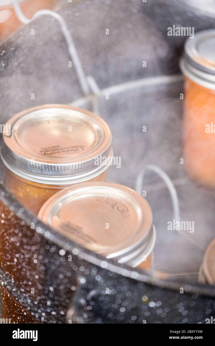 Jars of apricot jam resting on a canner rack in a boiling water canner