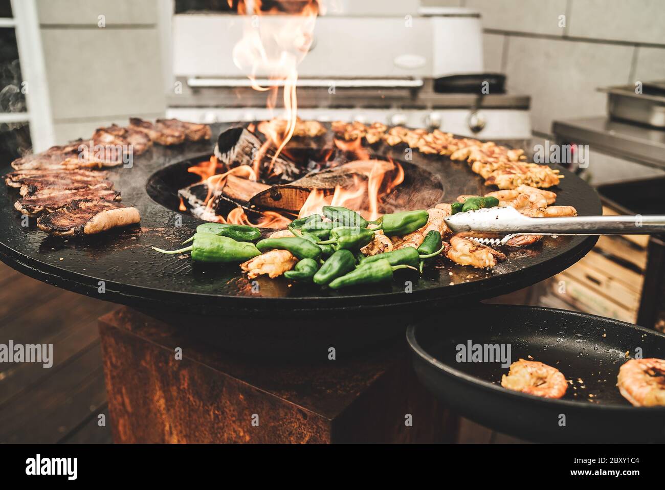 Round barbecue grill with open fire inside. Preparing meat pieces, shrimps  and green peppers. Party, BBQ, cooking and restaurant concept Stock Photo -  Alamy