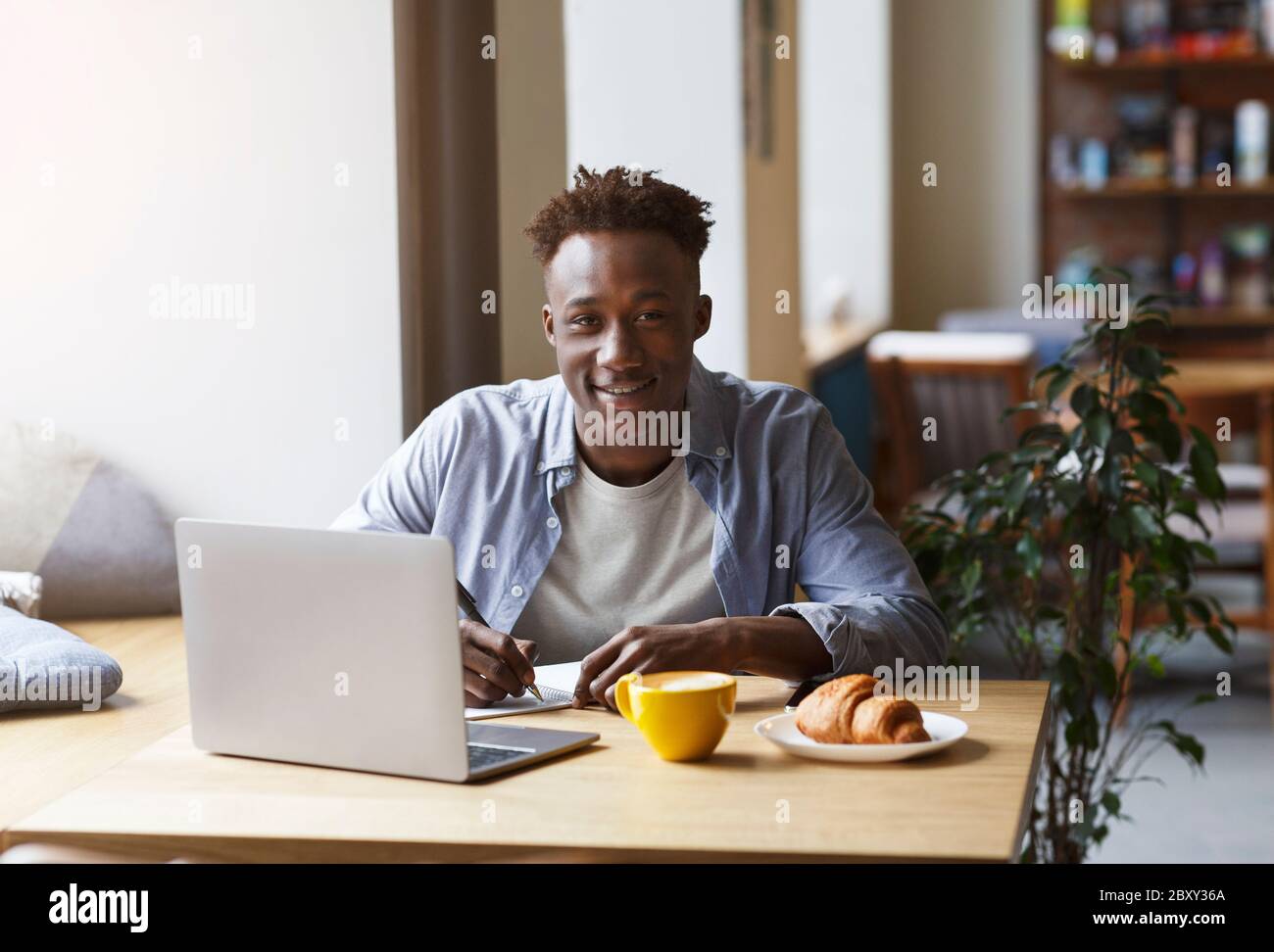 African American student with laptop doing homework in urban cafe Stock ...