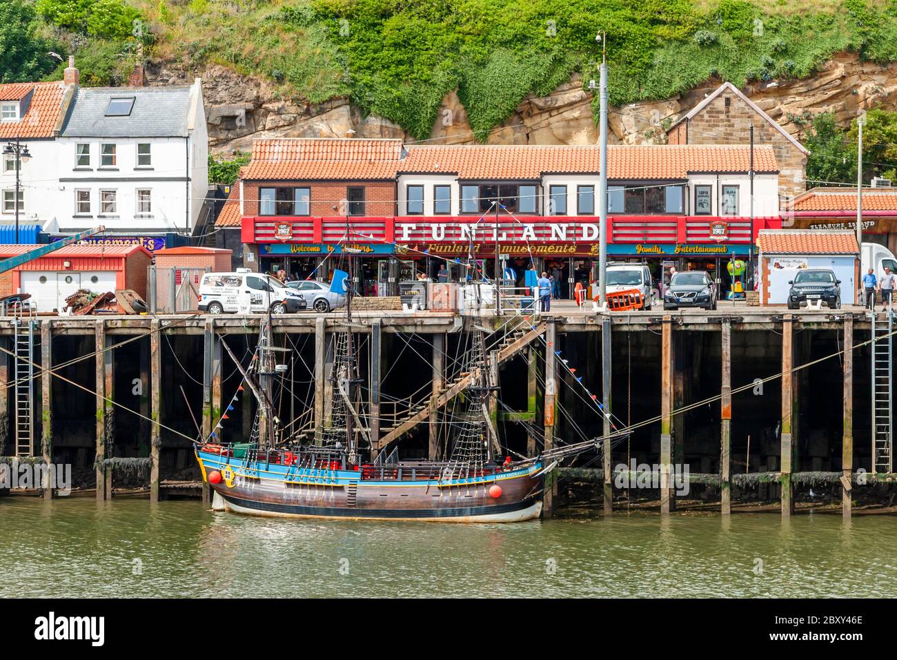 The Funland, Family Entertainment and Millers arcades at Whitby harbor, where the small three-master Bark Endeavour Whitby is moored, Scarborough, England Stock Photo