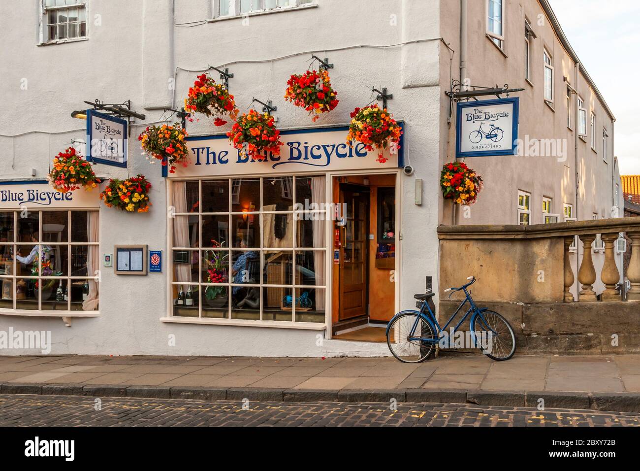 A blue bicycle parked outside the pub of the same name in Fossgate-Street in York, England Stock Photo