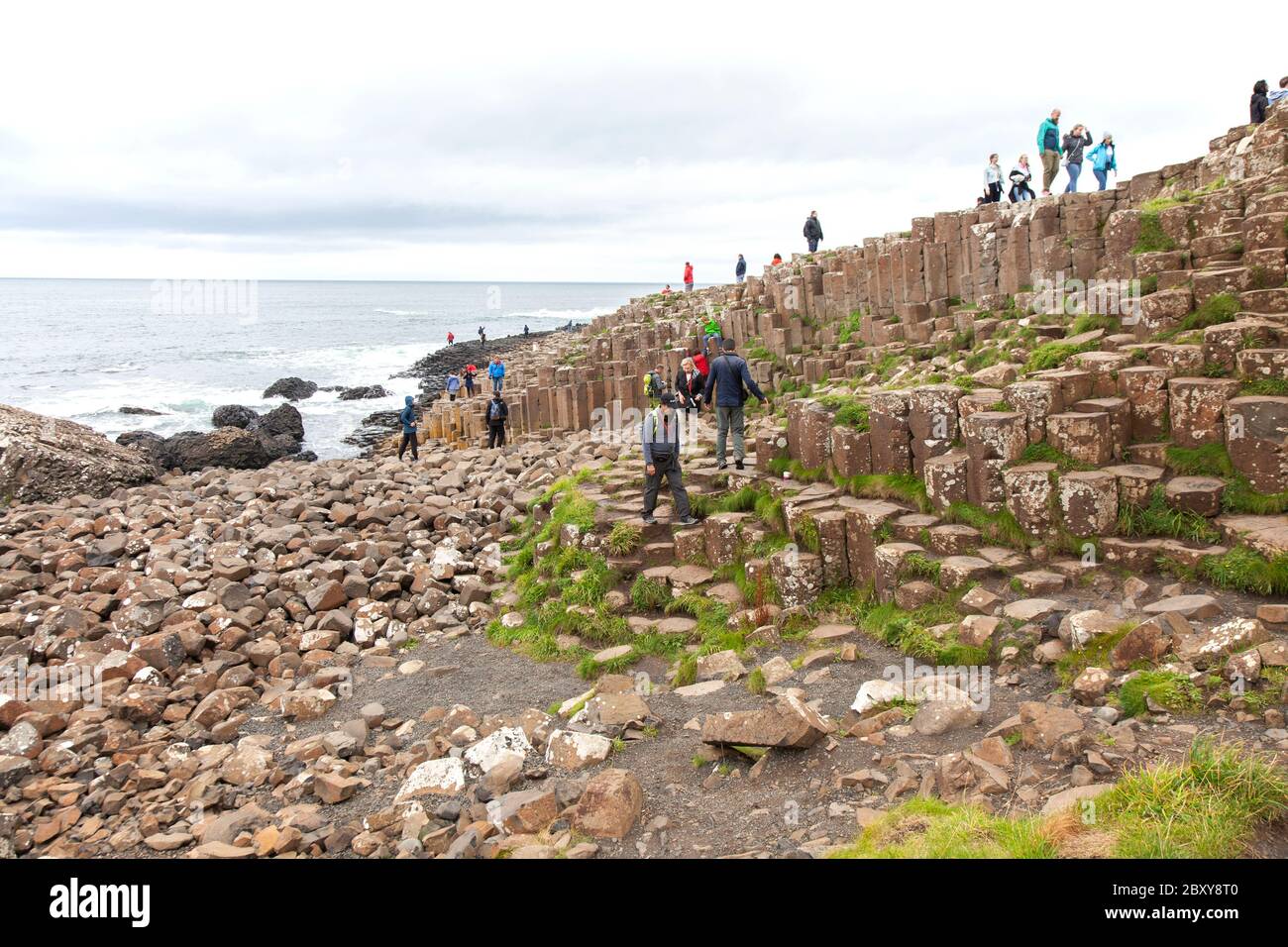 People exploring the thousands of ancient interlocking basalt columns of the Giant's Causeway on the north coast of County Antrim, Northern Ireland. Stock Photo