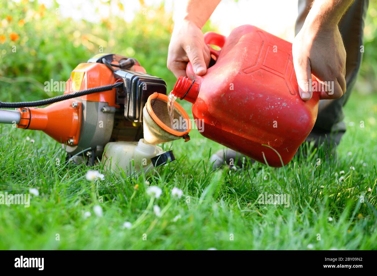 Gardener refueling brush cutter close up. Gardening tools maintenance. Lawn care with brush cutters .  Stock Photo