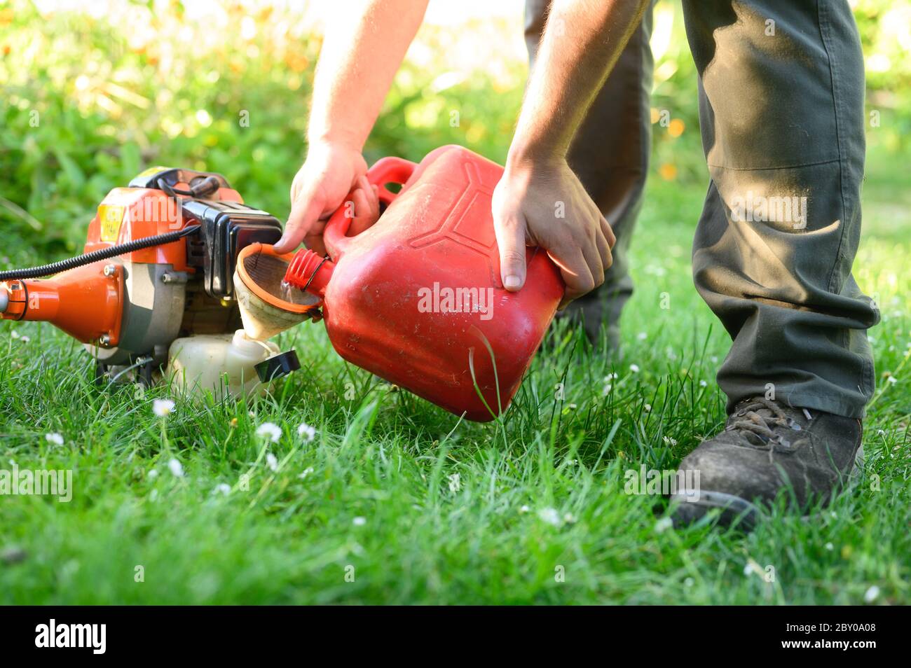 Gardener refueling brush cutter close up. Gardening tools maintenance. Lawn care with brush cutters .  Stock Photo