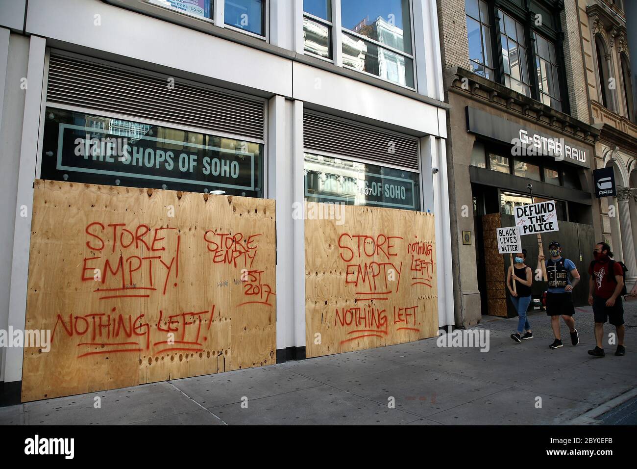 New York, USA. 4th June, 2020. Demonstrators holding placards walk past a boarded up store.Boarded up stores in parts of the city are seen after several nights of looting and fires in New York City. Protesters continue to march in support of racial justice in the boroughs of New York City as the Minneapolis Minnesota police officer, Derek Chauvin faces murder charges in the killing of George Floyd, in court. Credit: John Lamparski/SOPA Images/ZUMA Wire/Alamy Live News Stock Photo