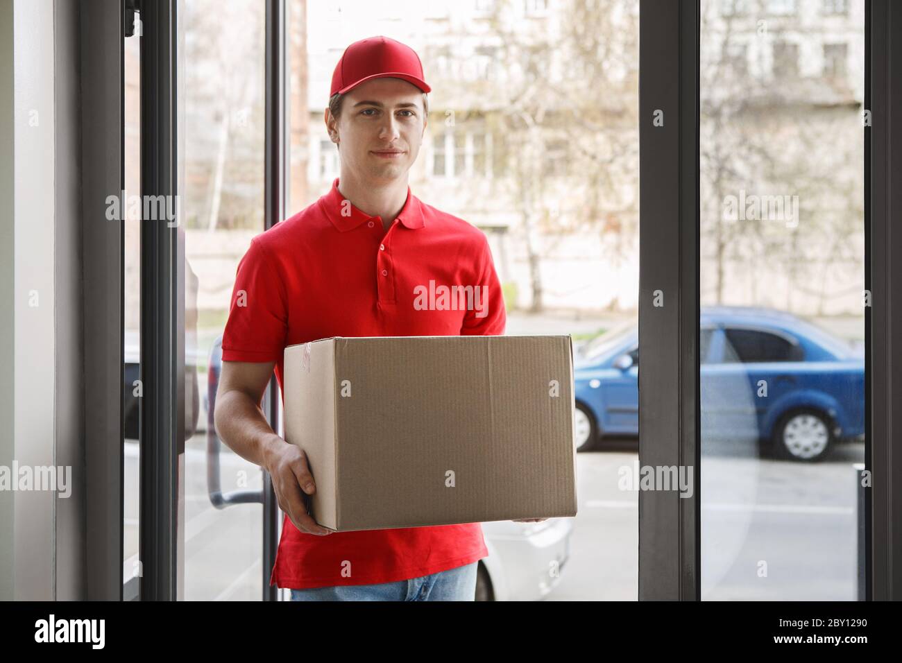 Convenient home delivery. Courier come at house and holding box Stock Photo