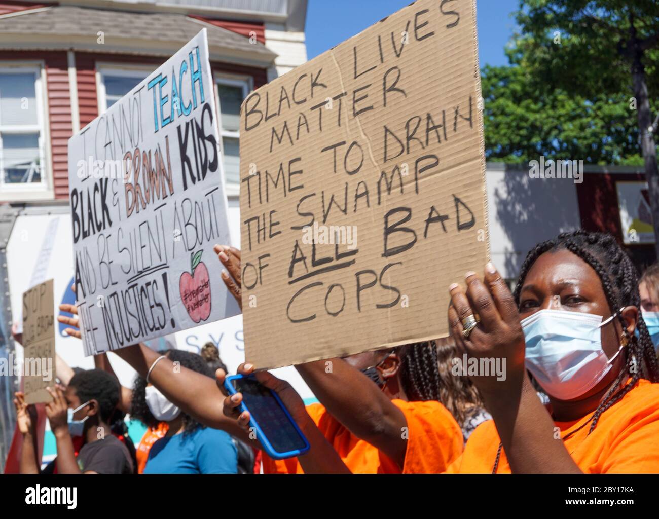 Black Lives Matter Protest George Floyd - Black Woman Holding Black Lives Matter Sign. Protesters line up with signs royalty free stock photograph - R Stock Photo