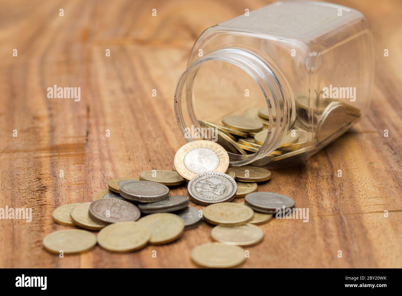 coins spilling out of glass jar Stock Photo