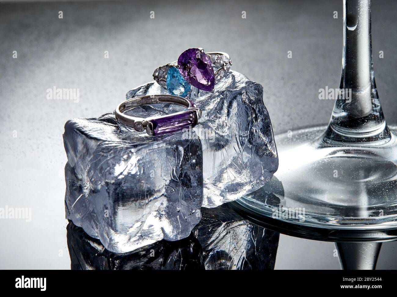 White gold rings with amethyst and blue topaz on ice cubes on a gray  background with reflection. Jewelry art and product sales Stock Photo -  Alamy