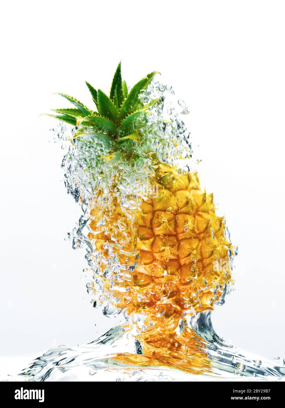 Bubbles forming in blue water after pineapple is dropped into it Stock