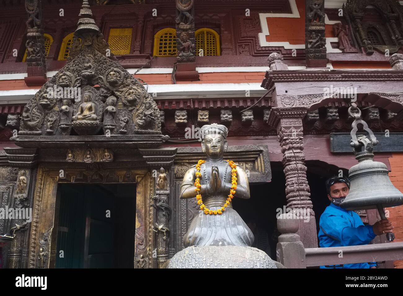 A worshipper rings a bell next to the brass statue of a former king, in ...