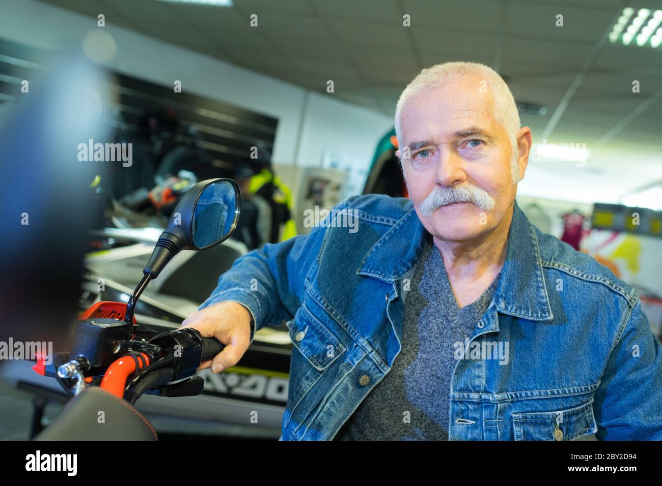 old man posing for picture while sitting on motorbike Stock Photo