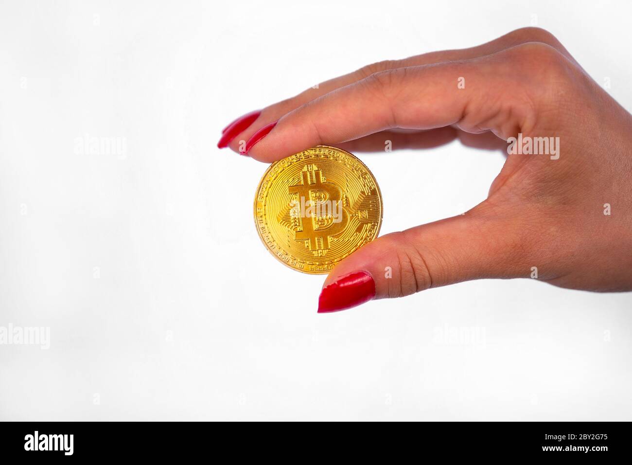 Virtual cryptocurrency money Bitcoin golden coin in the right hand of a woman with red nail polish. The future of money. Isolated on a white backgroun Stock Photo