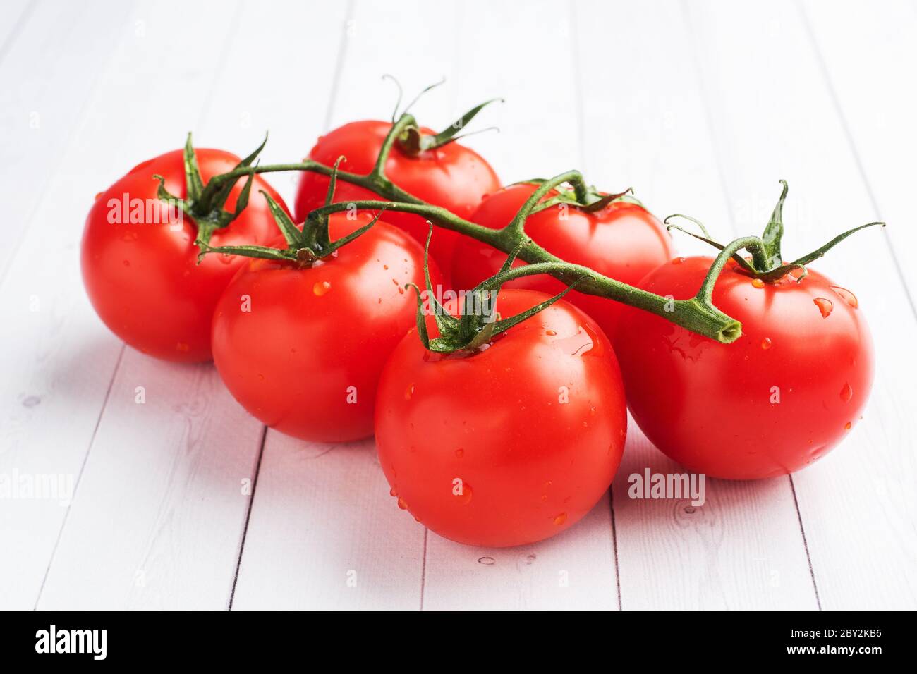 Cherry tomatoes on a branch. Fresh juicy red tomatoes on a white background. Copy space Stock Photo