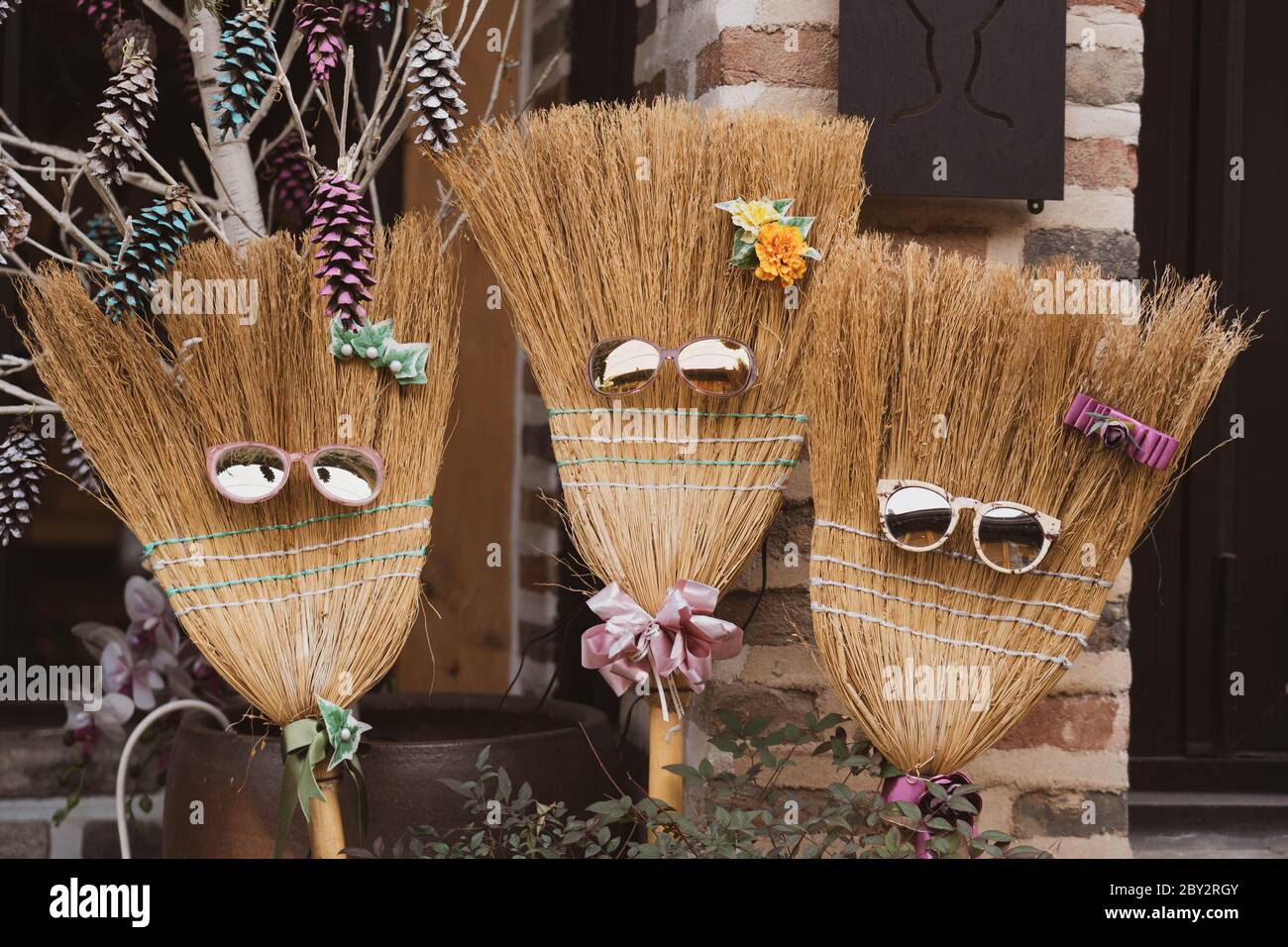 Decorative broom sticks wearing a sunglasses and flowers head pin and necktie. Stock Photo