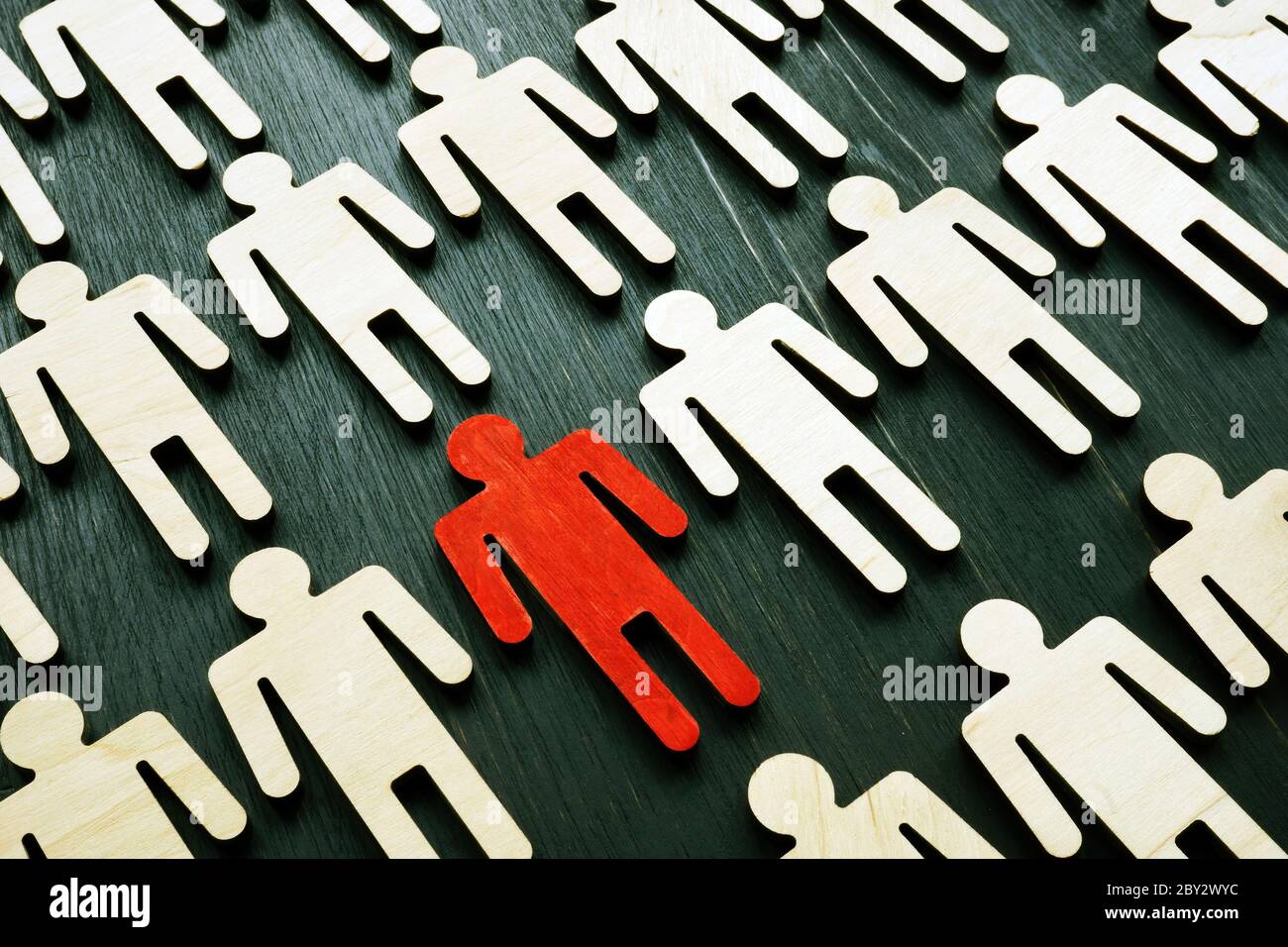 Be unique and different. Crowd from wooden figures and red one. Individuality and independence concept. Think outside the box. Stock Photo