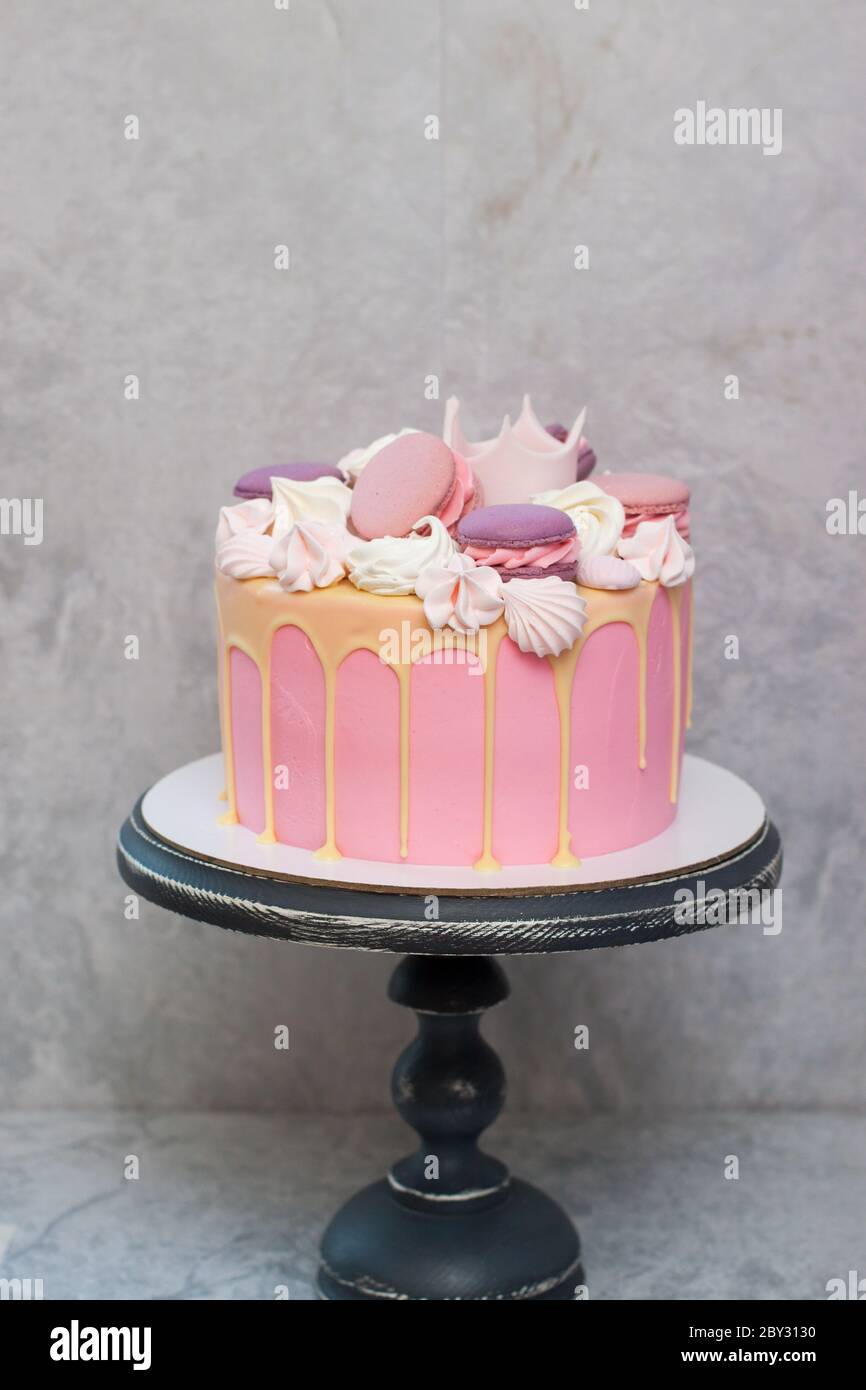 Birthday pink cake for a little girl with fondant crown, melted white  chocolate, meringue and cake pops on grey background Stock Photo - Alamy