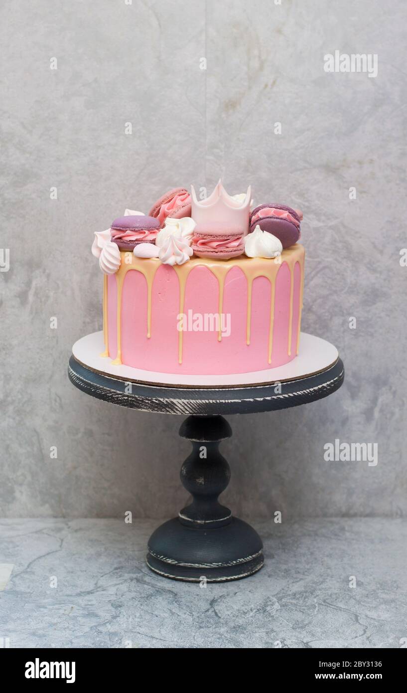 Birthday pink cake for a little girl with fondant crown, melted white  chocolate, meringue and cake pops on grey background Stock Photo - Alamy