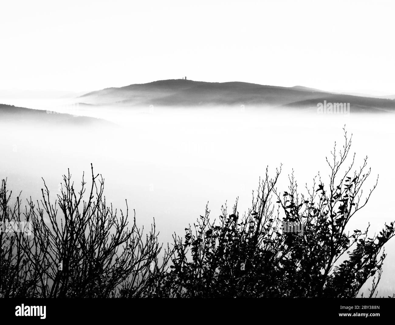 Cerchov Mountain above clouds in autumn inversion weather, Czech Republic. Black and white image. Stock Photo