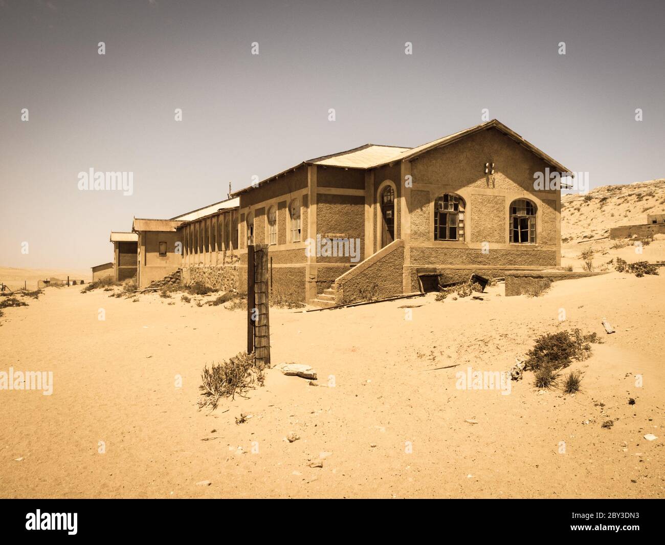 Ghost buildings of old diamond mining town Kolmanskop near Luderitz in Namibia. Abandoned house ruins sunken in the sand dunes of Namib Desert. Vintage toning photography. Stock Photo