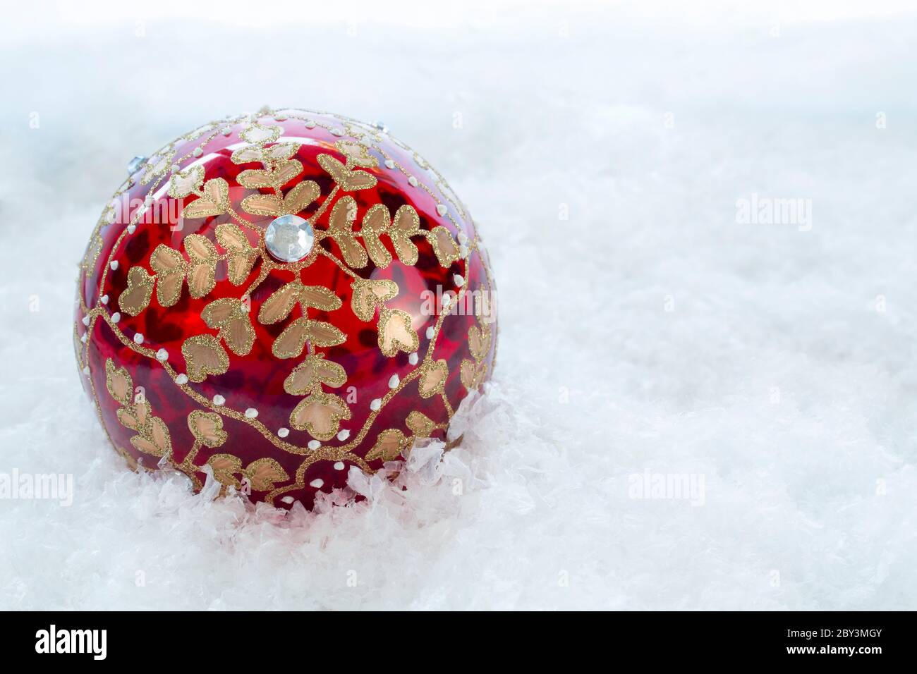 Ornate Christmas bauble on a snow covered  backdrop with copy space Stock Photo