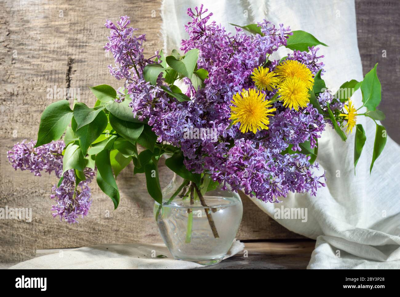 rustic still life with lilac in a glass vase and daisies wooden ...
