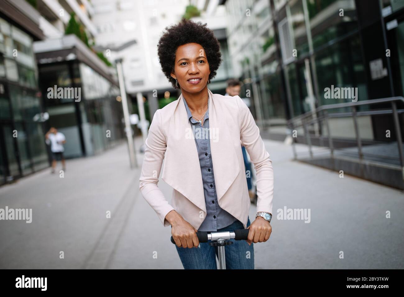 Beautiful woman riding an electric scooter to work, electric transport, ecological transport Stock Photo