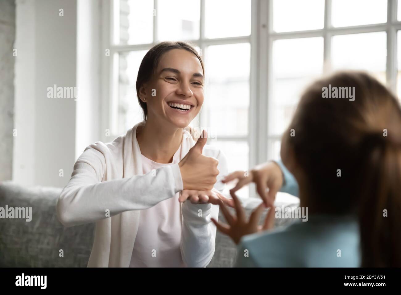 Smiling Caucasian woman learn sign language with little kid Stock Photo
