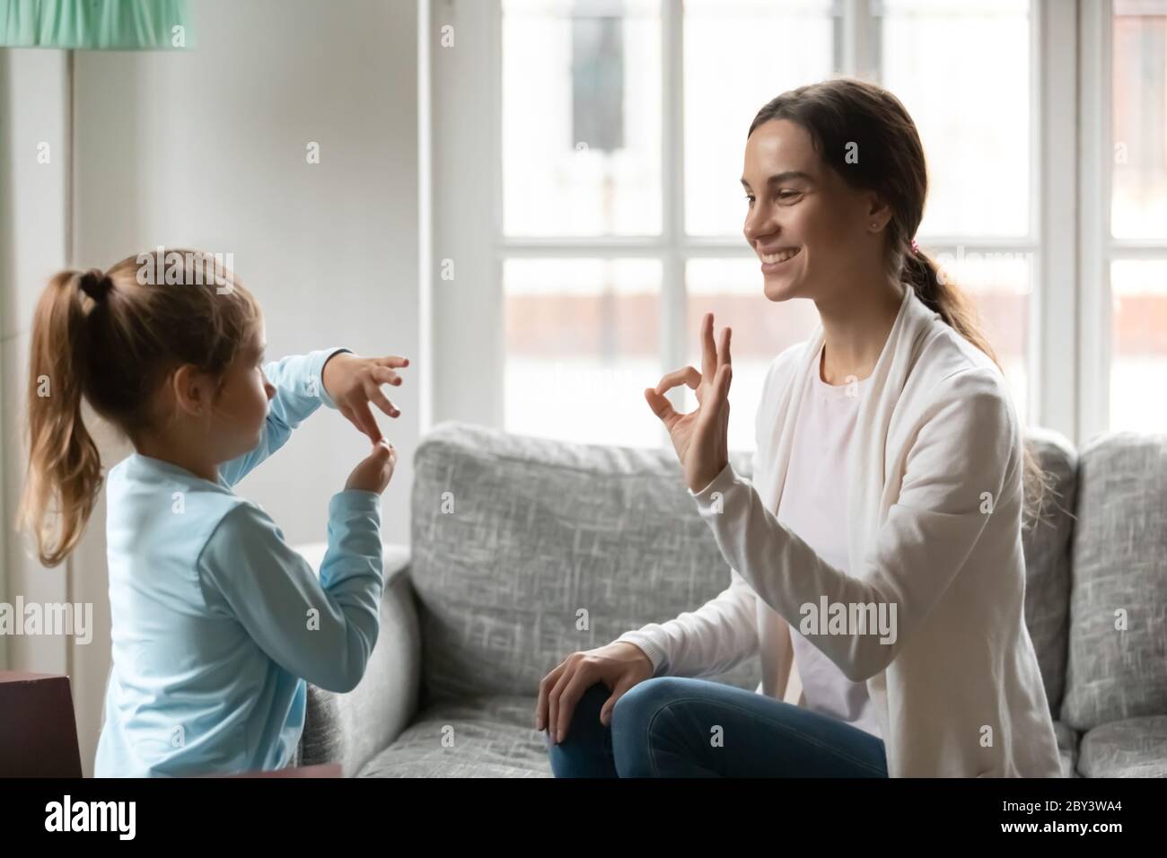 Young mom practice sign language with little daughter Stock Photo