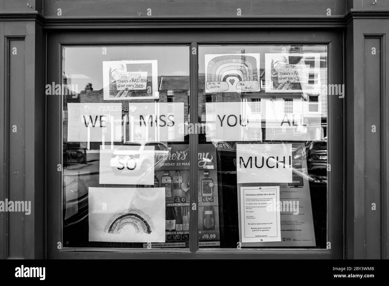 Monochrome view of a popular high street drinking establishment seen in lockdown. Messages of support and drawn rainbow images are seen in the window. Stock Photo