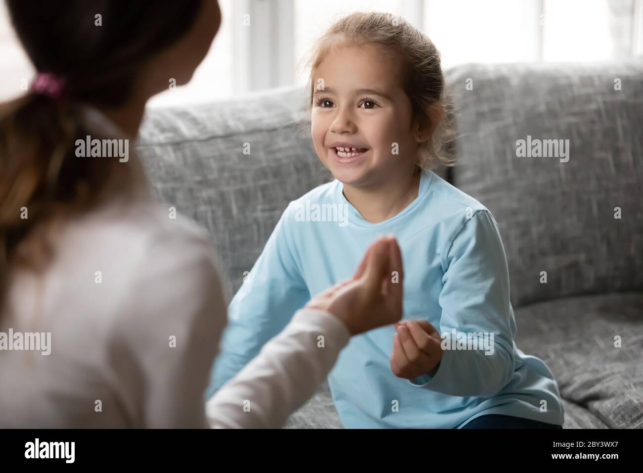 Little girl make hand gesture learn sign language with mom Stock Photo