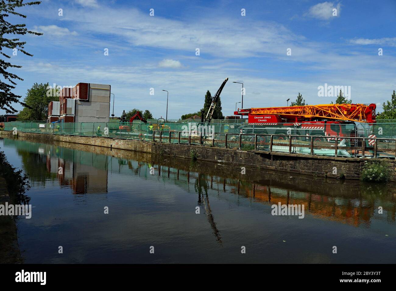 New modular homes and a old crane are reflected in the canal as they are being built alongside the Leeds and Liverpool canal opposite Wigan Pier Stock Photo