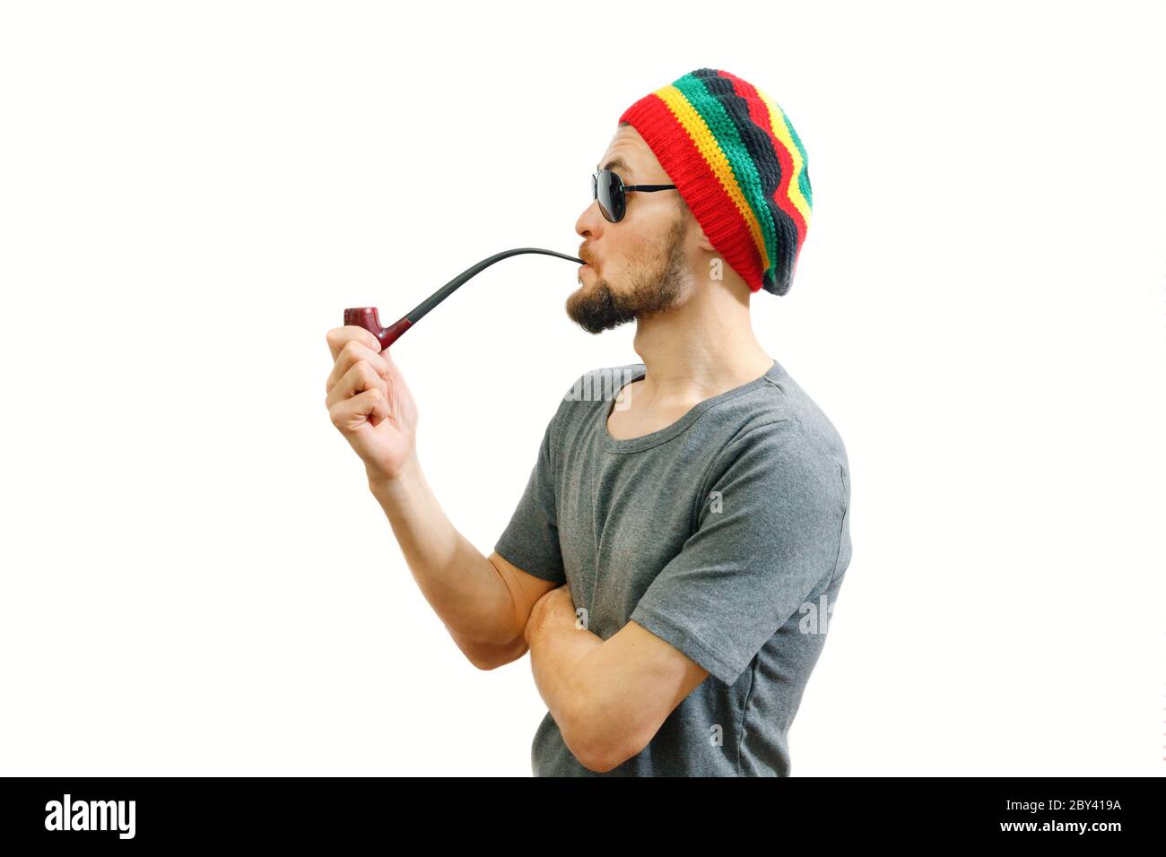 Young caucasian rasta man in jamaica hat, sunglasses and grey t-shirt on  white background with smoke pipe in hand Stock Photo - Alamy